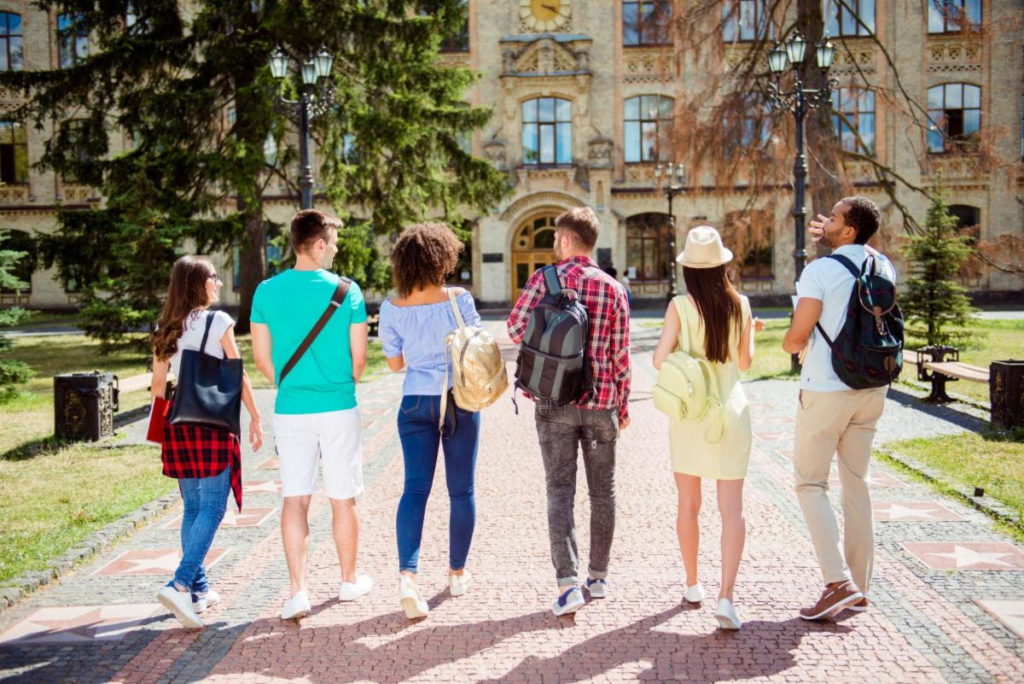 Young people wearing backpacks walking away