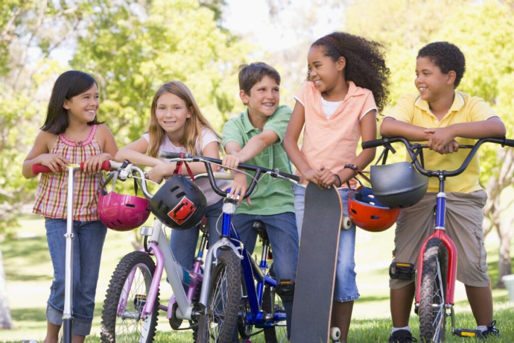 5 young teenagers of various ethnicities posing with their bikes