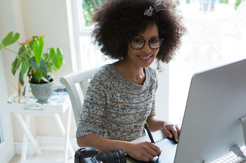 a young black woman sitting at her computer smiling