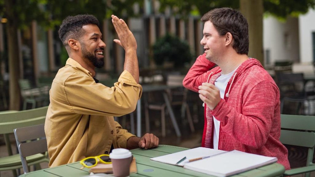 A coach and student sitting at a table high-fiving each other
