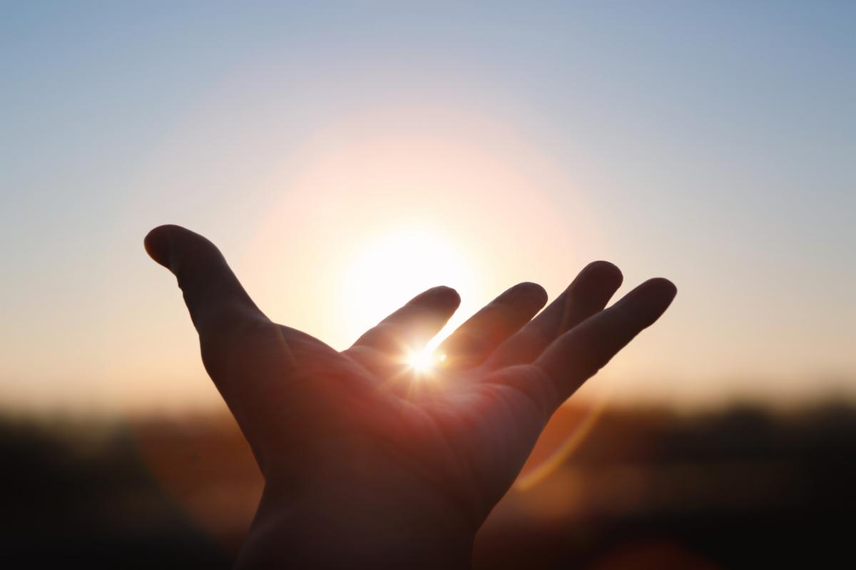 a hand extended towards the sun